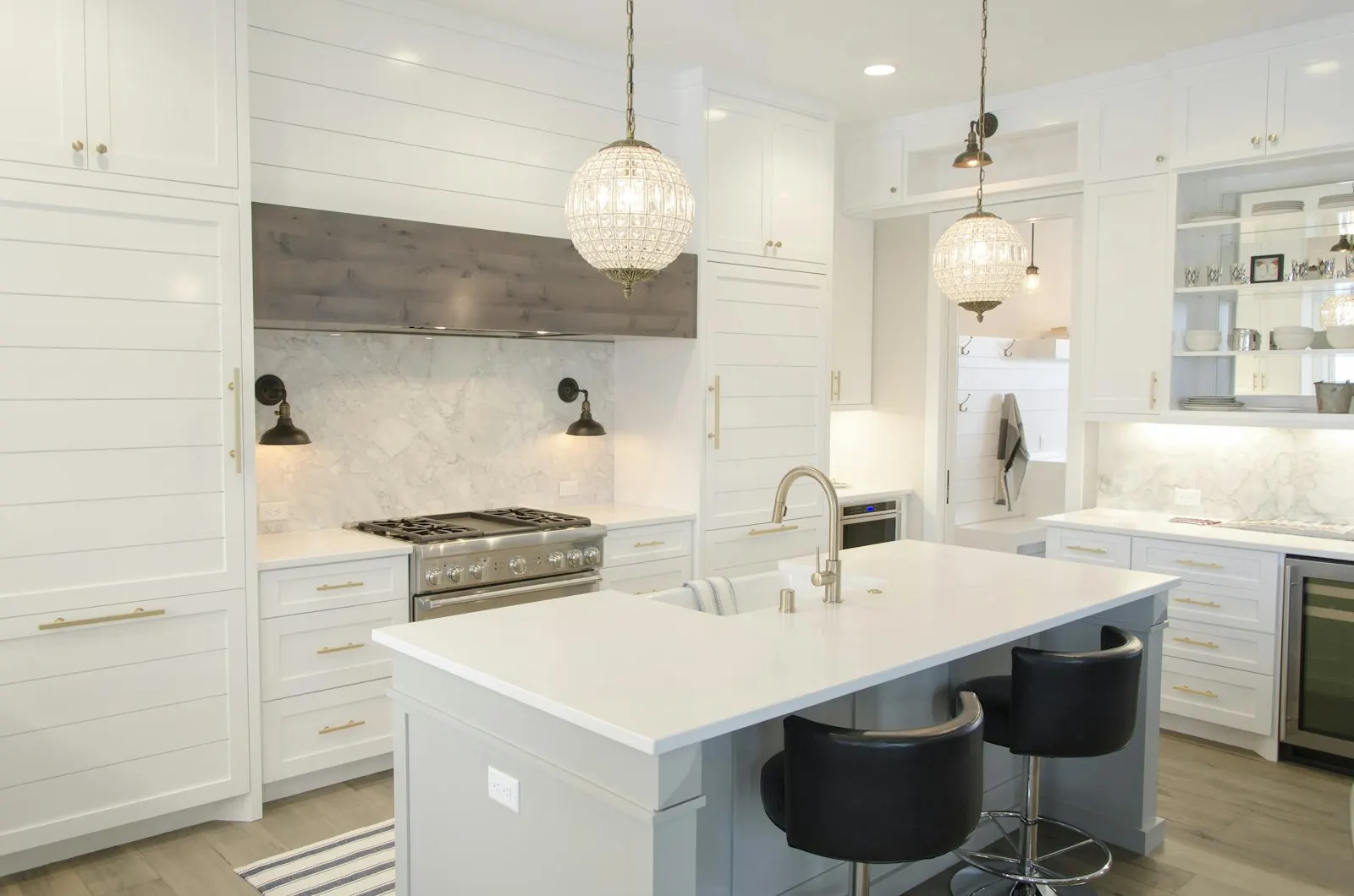 Island kitchen with bar seating, glossy cabinetry and layered pendant lighting