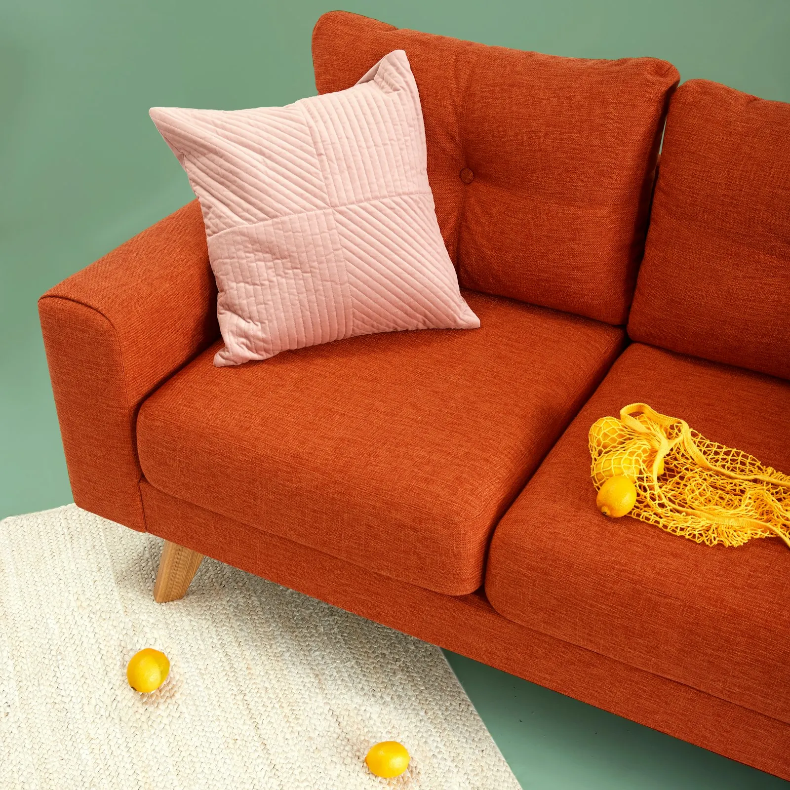 Rust-orange sofa with textured cushions and a monochrome art ledge above